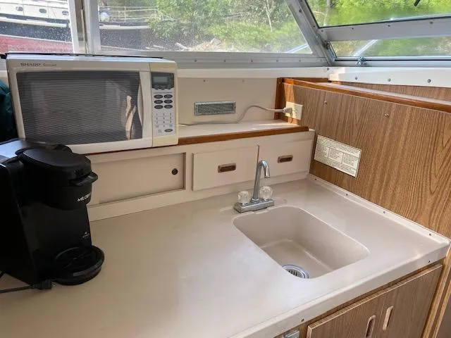 Slide: The Image of 1972 Bertram Express boat kitchen with sink, microwave, and coffee maker. - 9