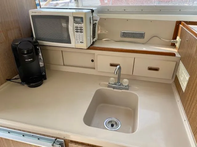 Slide: The Image of 1972 Bertram Express kitchen with sink, microwave, and coffee maker on beige countertop. - 10