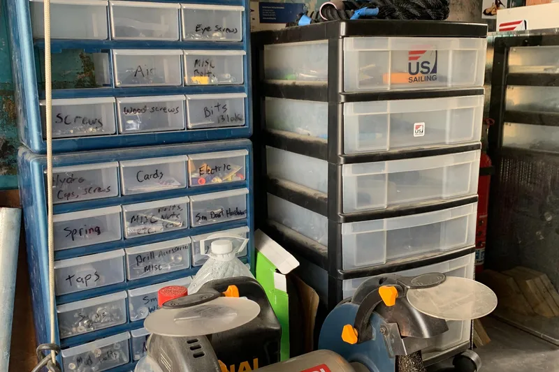 Slide: The Image of Organized workshop storage with labeled drawers and tools, featuring US Sailing logo. - 19