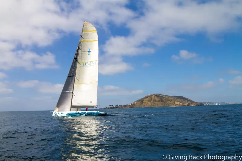 Slide: The Image of Sailing yacht "Americas Cup Class 75" on open sea near a coastal hill, 2000. - 2