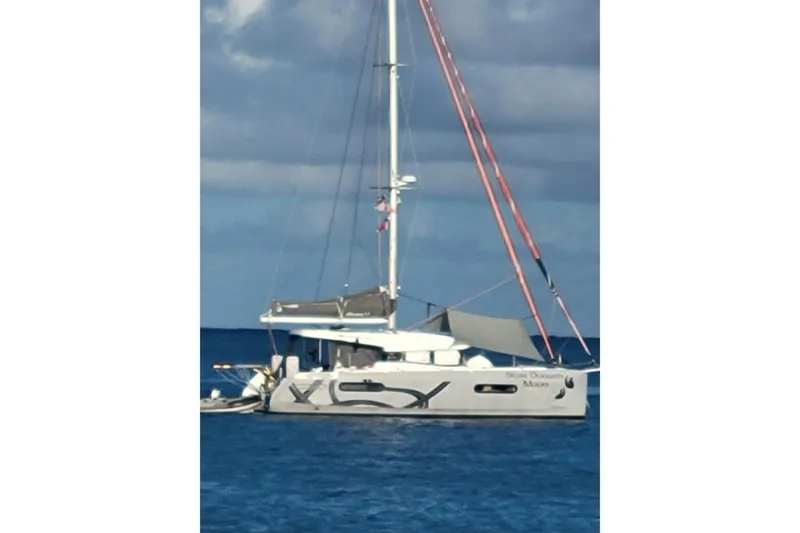 Slide: The Image of Sailing catamaran Excess 12, 2020 model, anchored on calm blue sea under cloudy sky. - 0