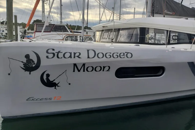 Slide: The Image of Catamaran "Star Dogged Moon" docked, featuring "Excess 12" branding, 2020 model. - 1