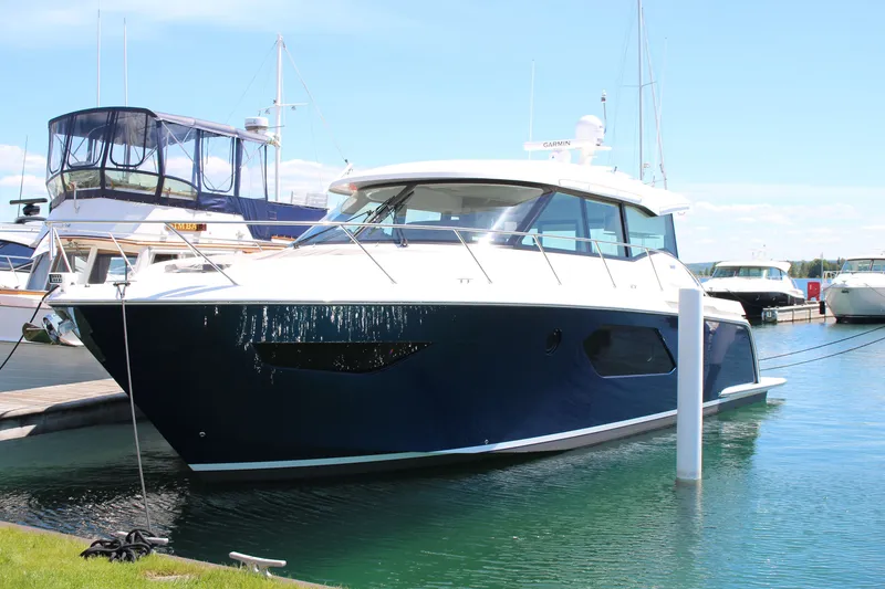 The Image of 2020 Tiara Yachts C49 Coupe docked in a marina under clear blue skies. - 0