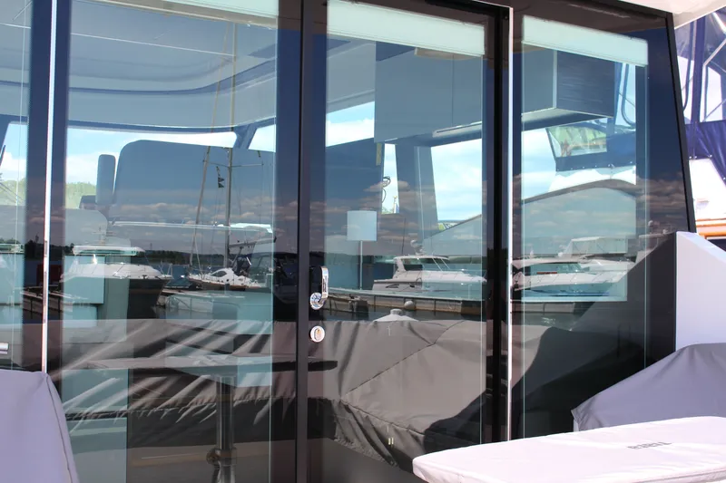 Slide: The Image of 2020 Tiara Yachts C49 Coupe with reflective glass doors at a marina. - 15