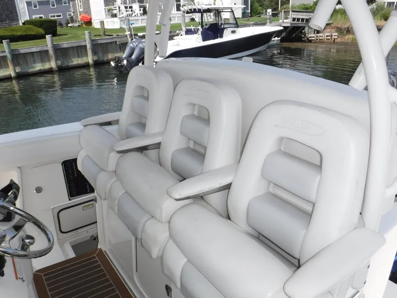 Slide: The Image of 2014 Boston Whaler 370 Outrage boat with white cushioned seating, docked near waterfront homes. - 46