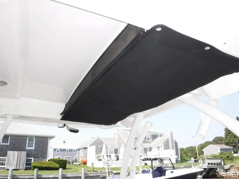 Slide: The Image of 2014 Boston Whaler 370 Outrage boat with black canopy, docked near waterfront homes. - 47
