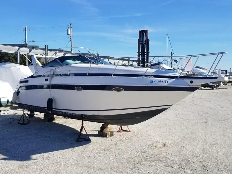 Slide: The Image of 1992 Baja 340 Motoryacht on dry dock, white hull, blue stripe, clear sky background. - 5
