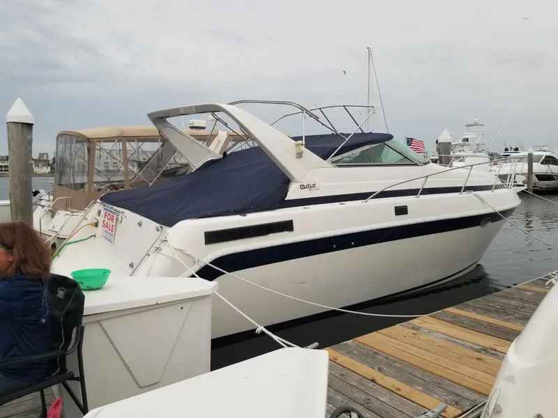 Slide: The Image of 1992 Baja 340 Motoryacht docked, white hull, blue cover, "For Sale" sign visible. - 6