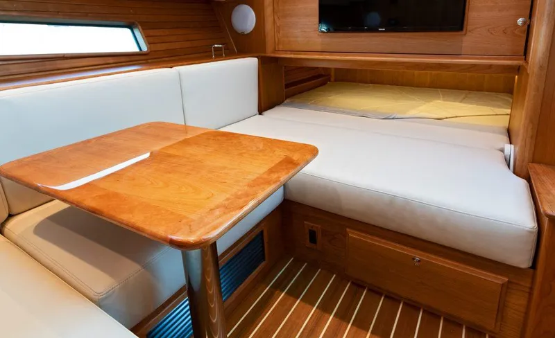 Slide: The Image of Interior of 2025 Sabre 43 Salon Express with wooden table and cushioned seating. - 27