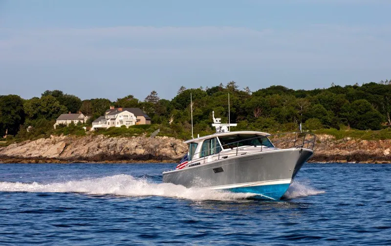 Slide: The Image of 2025 Sabre 43 Salon Express cruising near a coastal estate. - 3