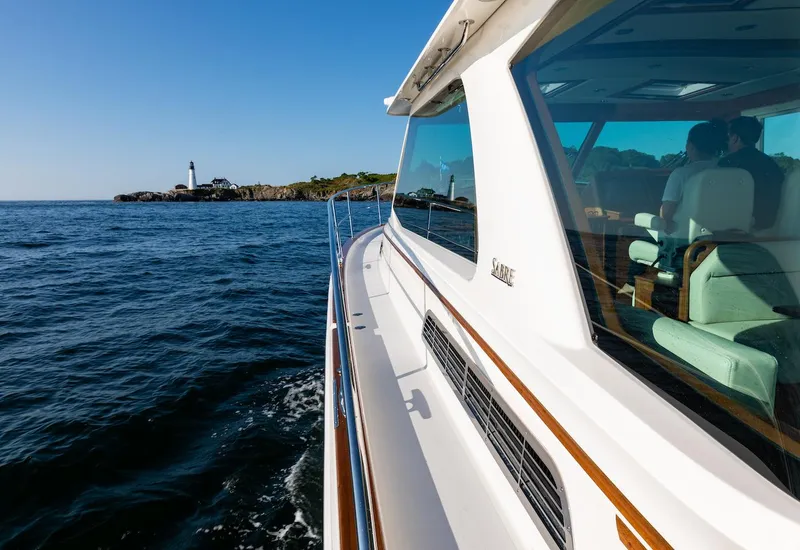 Slide: The Image of 2025 Sabre 43 Salon Express yacht cruising near a lighthouse. - 7