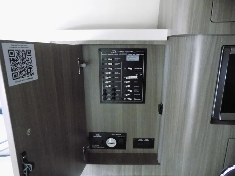Slide: The Image of Electrical panel inside 2019 Regal 28 Express boat with open cabinet door. - 18
