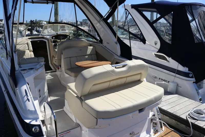 Slide: The Image of 2019 Regal 28 Express boat interior with beige seating and wooden table, docked at marina. - 20