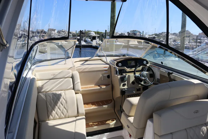 Slide: The Image of 2019 Regal 28 Express boat interior with beige seating and modern dashboard at a marina. - 24