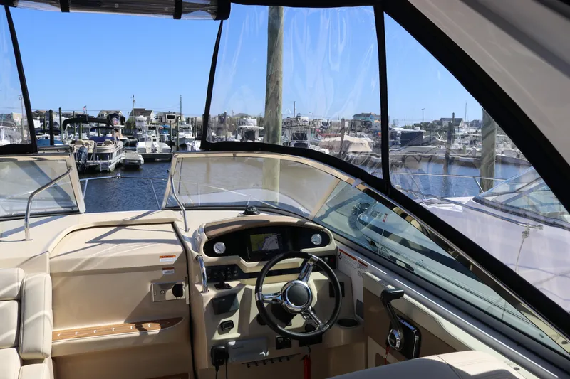 Slide: The Image of 2019 Regal 28 Express boat interior with marina view, featuring steering wheel and dashboard. - 25