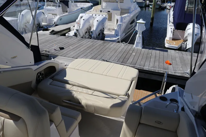 Slide: The Image of 2019 Regal 28 Express boat interior with beige seating at a marina dock. - 27