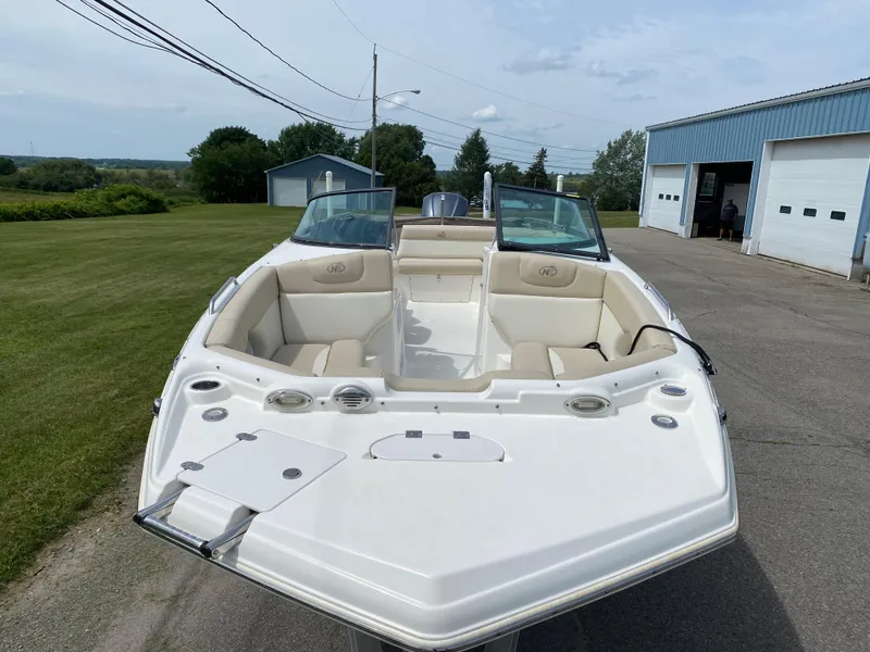 Slide: The Image of 2018 NauticStar 243DC Sport Deck boat with beige seating, docked near a blue building. - 4