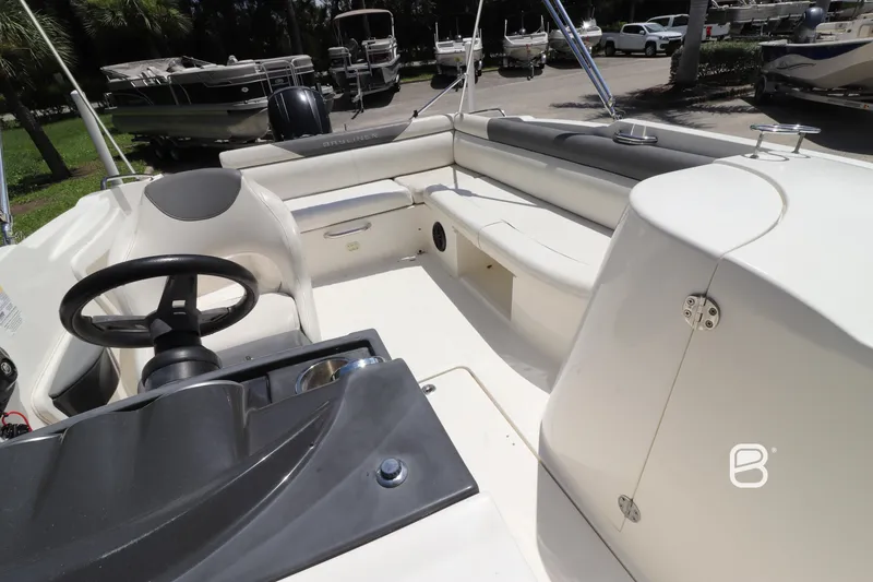 Slide: The Image of 2018 Bayliner 210 DB boat interior with steering wheel and seating area. - 13