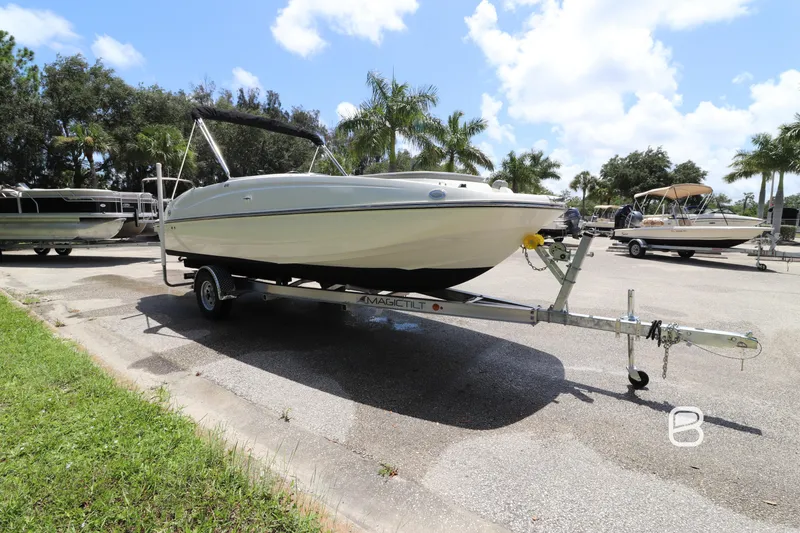 Slide: The Image of 2018 Bayliner 210 DB boat on trailer, parked outdoors under a sunny sky. - 3