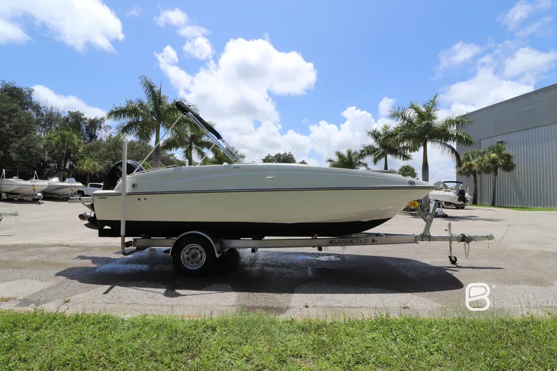 Slide: The Image of 2018 Bayliner 210 DB boat on trailer, parked outdoors with palm trees and blue sky. - 4