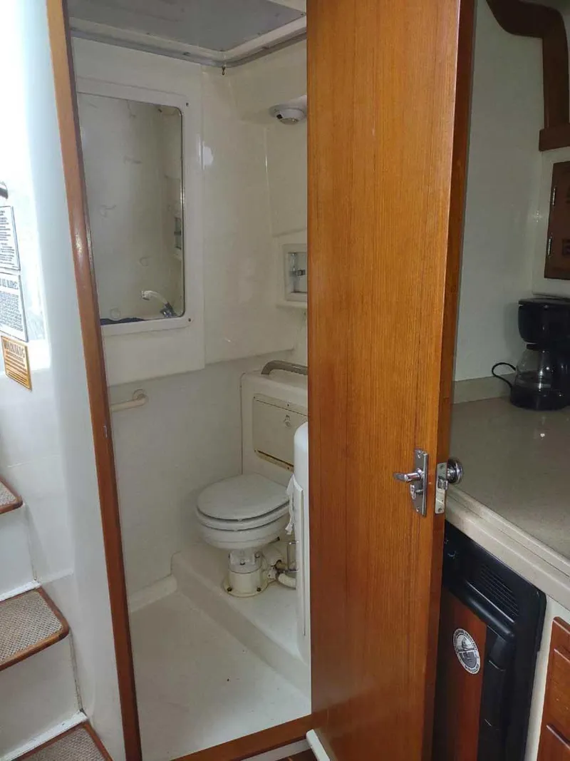 Slide: The Image of 1998 Cabo 31 Express boat interior with compact bathroom and wooden door. - 12