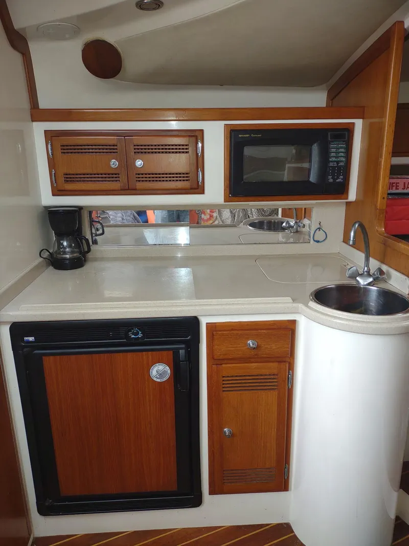Slide: The Image of Compact kitchen in 1998 Cabo 31 Express boat with wood cabinets, microwave, and sink. - 18
