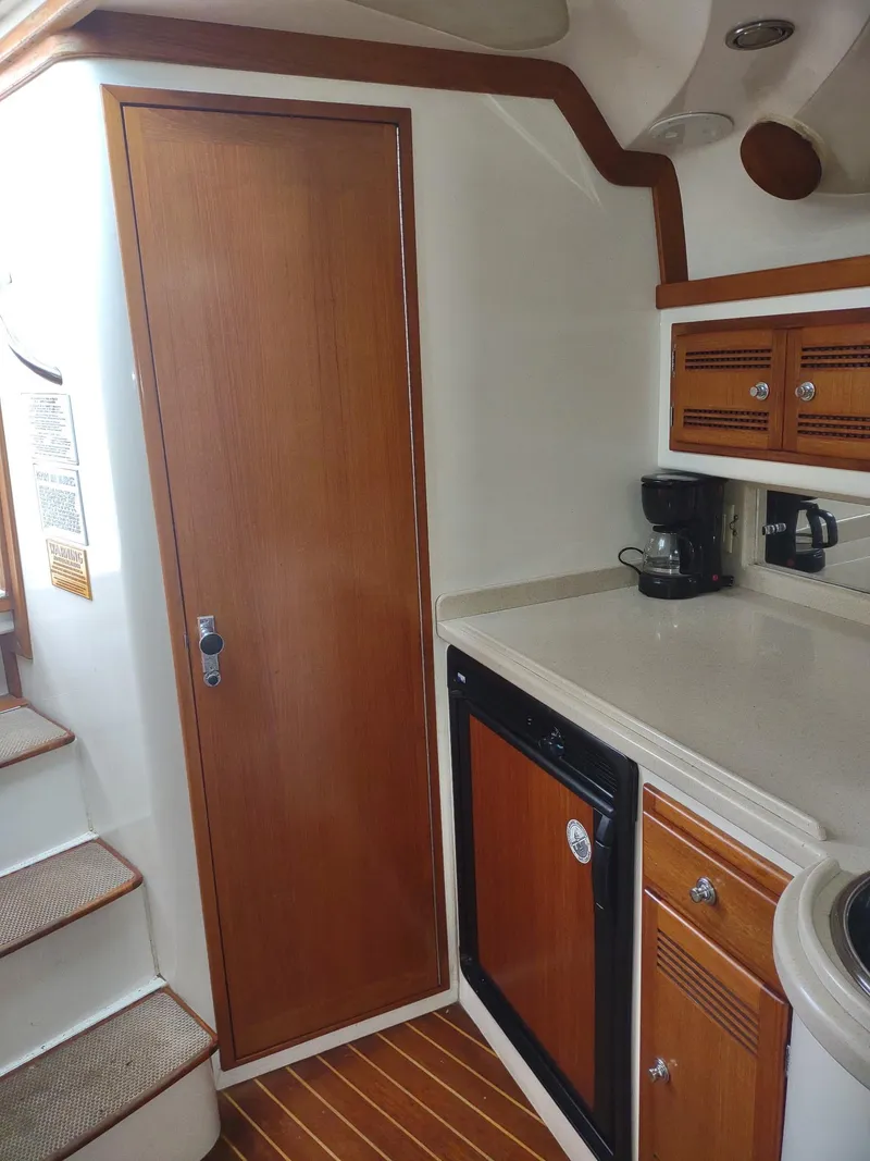 Slide: The Image of 1998 Cabo 31 Express yacht interior with kitchenette, wooden cabinets, and stairs. - 19