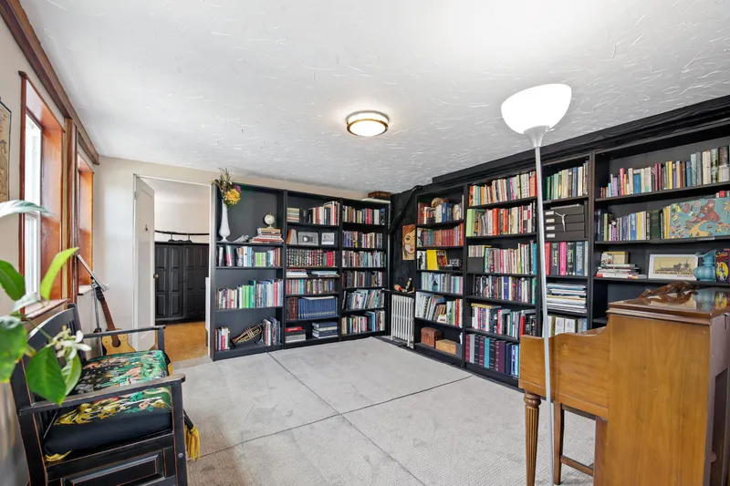 Slide: The Image of Cozy home library with black bookshelves, wooden desk, and floral chairs. - 15