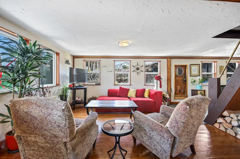 Slide: The Image of Cozy living room with vintage decor, red sofa, patterned armchairs, and wooden accents. - 20