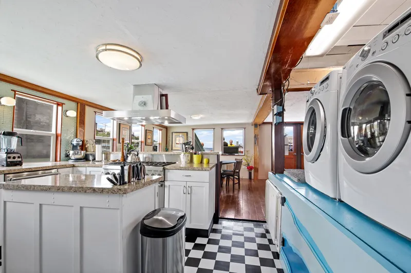 Slide: The Image of 1938 Custom Ferry interior with modern kitchen and laundry area, featuring checkered flooring and granite countertops. - 26
