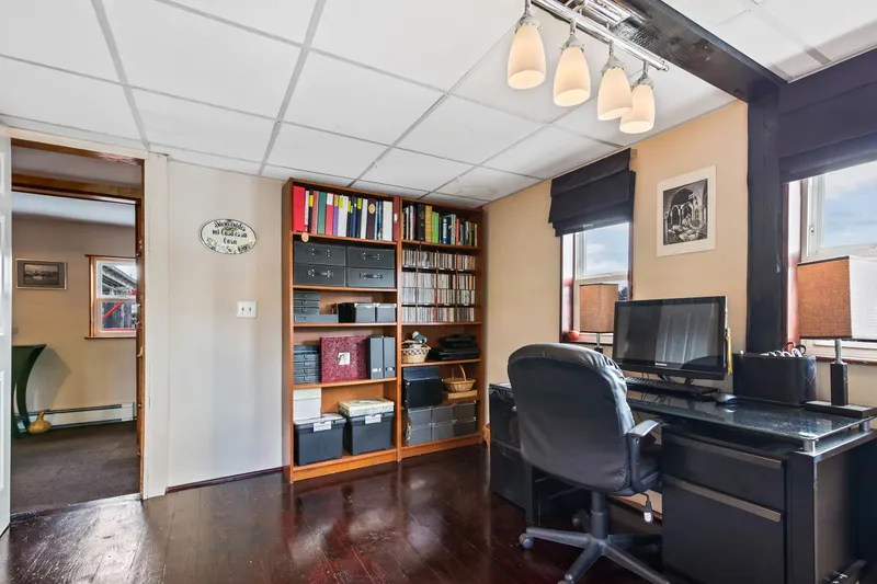 Slide: The Image of Home office with dark wood flooring, desk, chair, bookshelves, and ceiling lights. - 37