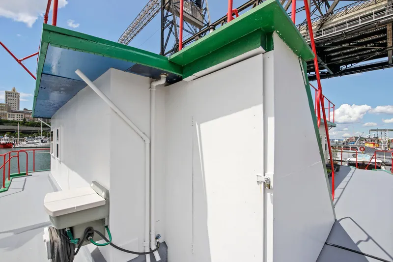 Slide: The Image of 1938 Custom Ferry exterior with white and green paint, docked near a bridge. - 44