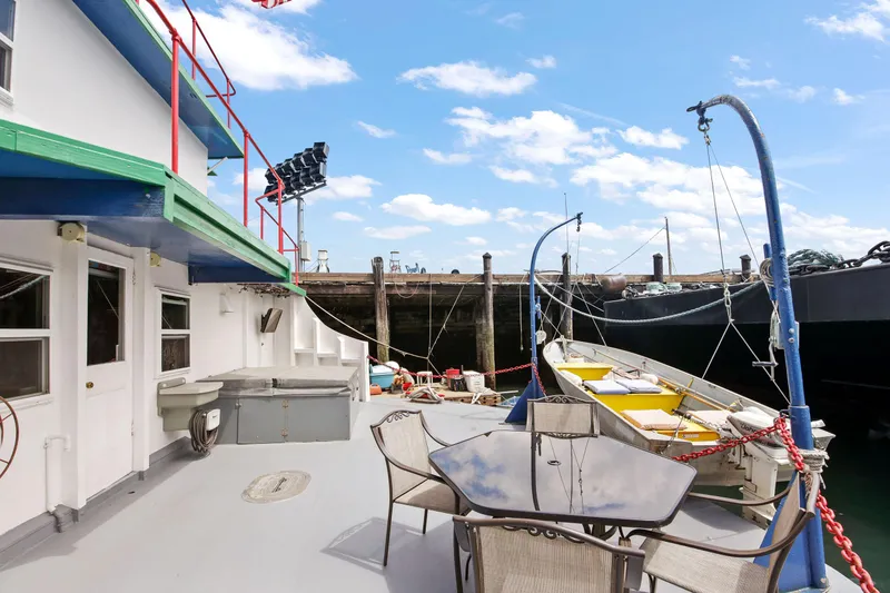 Slide: The Image of 1938 Custom Ferry deck with outdoor seating and docked boat under clear sky. - 48