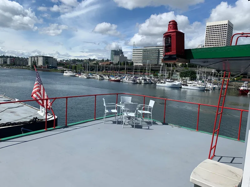 Slide: The Image of 1938 Custom Ferry deck with chairs, American flag, and waterfront cityscape. - 9
