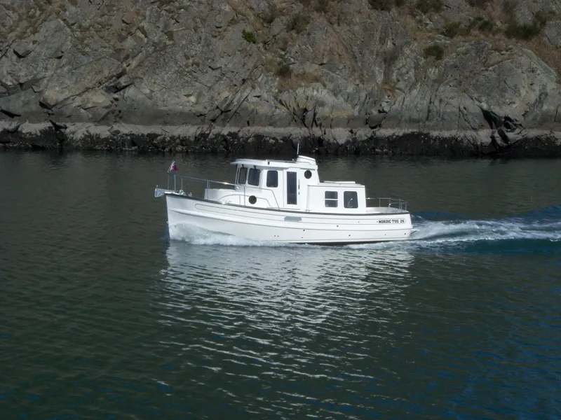 The Image of 2025 Nordic Tug 26 cruising near rocky shoreline. - 0