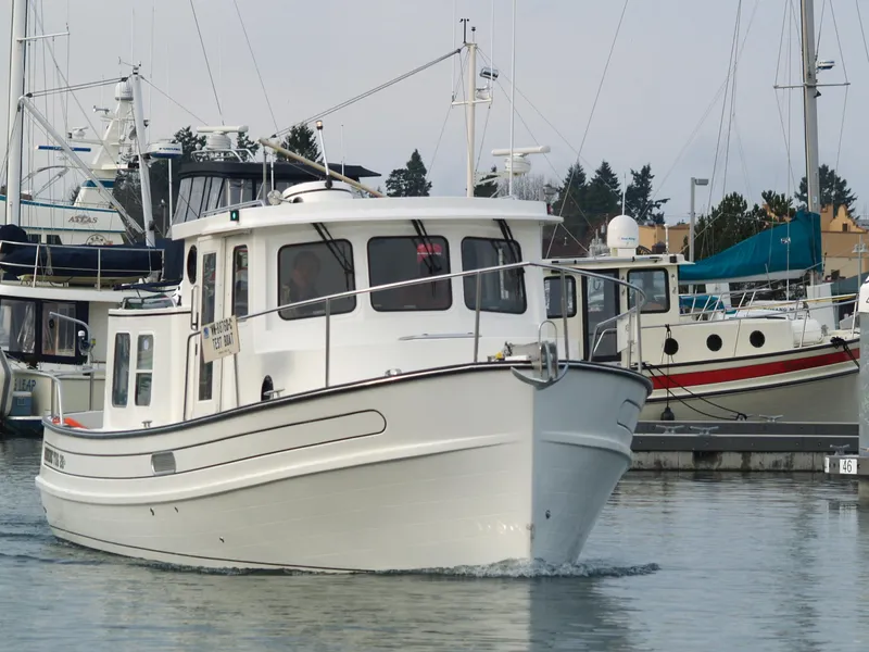 Slide: The Image of 2025 Nordic Tug 26 cruising in a marina with other boats docked. - 2