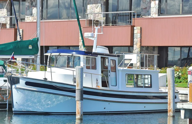 Slide: The Image of 2025 Nordic Tug 34 docked at a marina with waterfront buildings in the background. - 8
