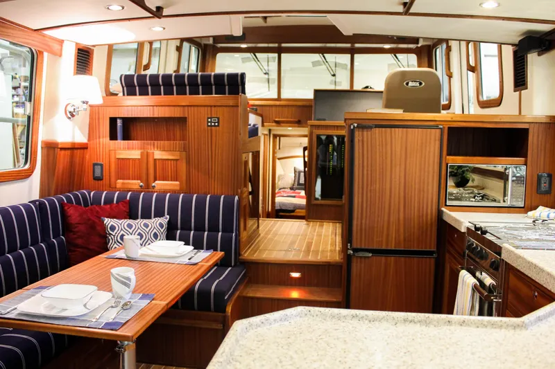 Slide: The Image of Interior of 2025 Nordic Tug 40, featuring dining area, kitchen, and helm station. - 3
