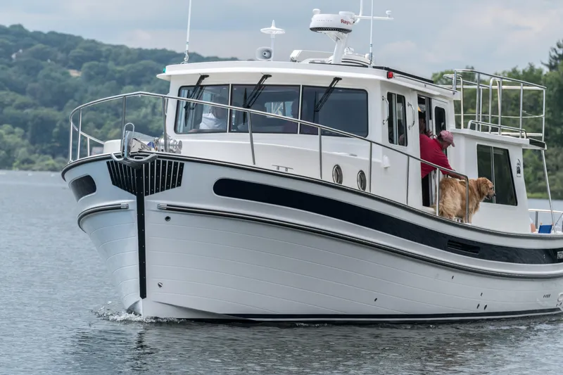 Slide: The Image of 2025 Nordic Tug 40 cruising on a lake with a person and a dog on deck. - 16