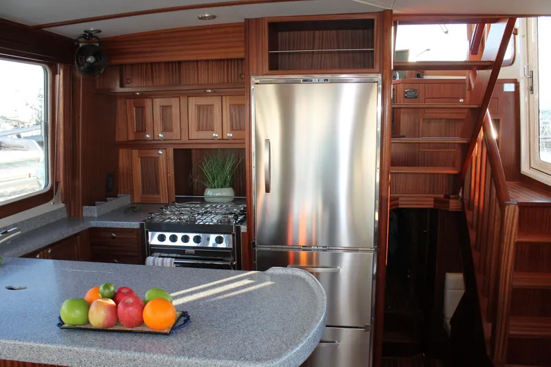 Slide: The Image of 2025 Nordic Tug 44 kitchen with stainless steel appliances and wooden cabinetry. - 1