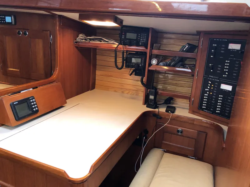 Slide: The Image of Navigation station in a 1995 Valiant 50 yacht with wood paneling and electronic equipment. - 21