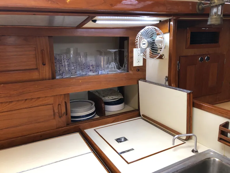 Slide: The Image of Valiant 50 yacht kitchen, 1995 model, featuring wooden cabinetry, sink, fan, and neatly arranged dishes. - 26