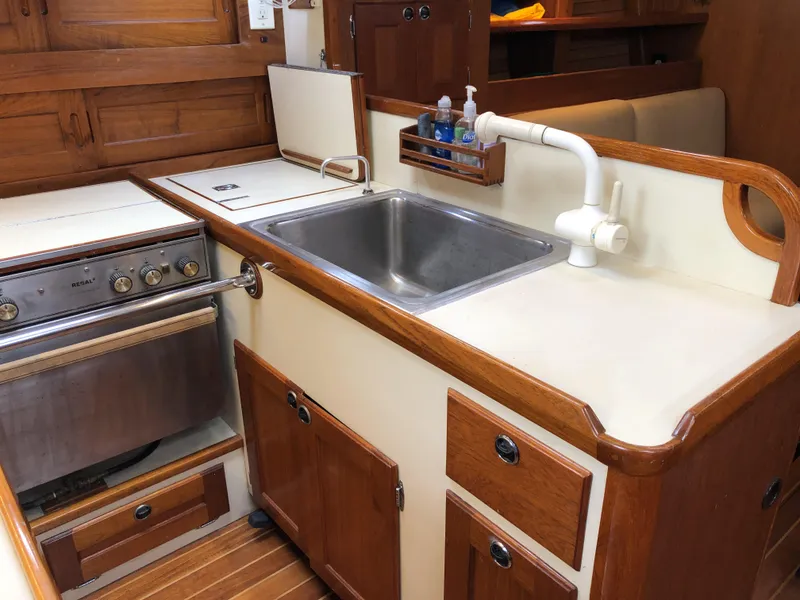 Slide: The Image of Compact kitchen area in a 1995 Valiant 50 yacht with wooden cabinetry and stainless steel sink. - 28