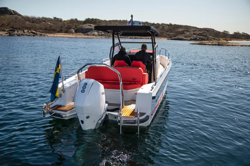 Slide: The Image of 2025 Nimbus T8 motorboat cruising on a scenic lake with rocky shoreline. - 2