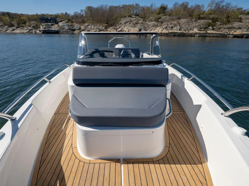 Slide: The Image of 2025 Nimbus T8 boat with teak deck and cushioned seating, docked near rocky shoreline. - 8
