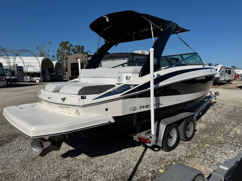 Slide: The Image of 2013 Regal 2500 Bowrider boat on trailer, parked outdoors under clear blue sky. - 4