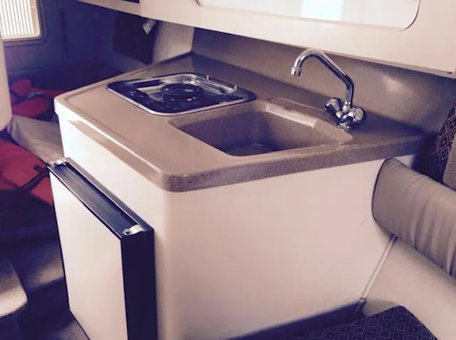 Slide: The Image of Compact kitchen area in a 1998 Doral 2500 SC boat with sink and stove. - 3