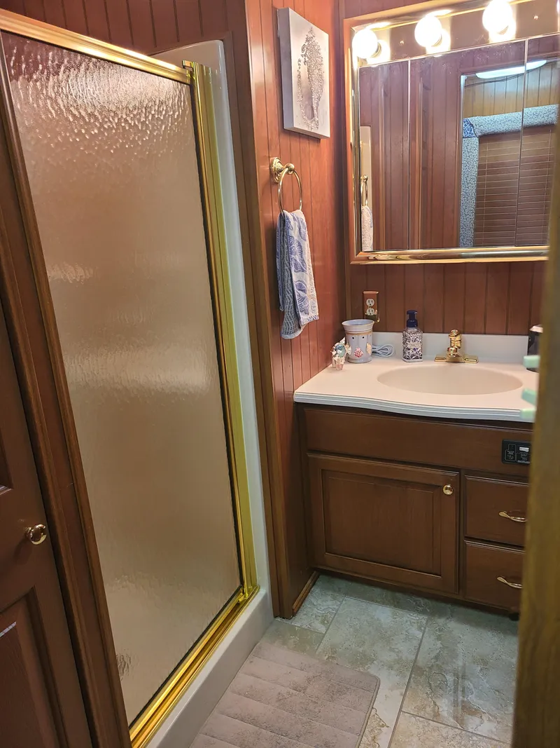 Slide: The Image of Bathroom interior of a 2003 Monticello River Yacht with wooden cabinets and a glass shower door. - 12
