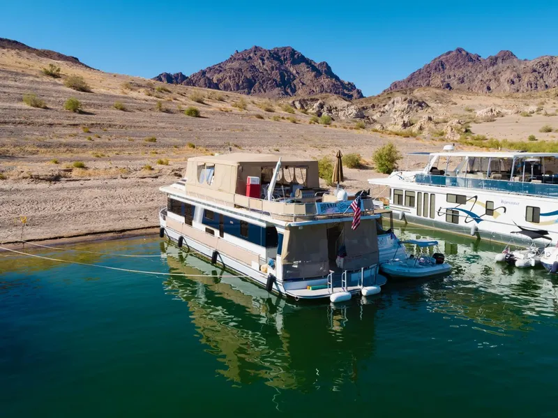 Slide: The Image of 2003 Monticello River Yacht docked in a scenic desert lake with mountains in the background. - 2