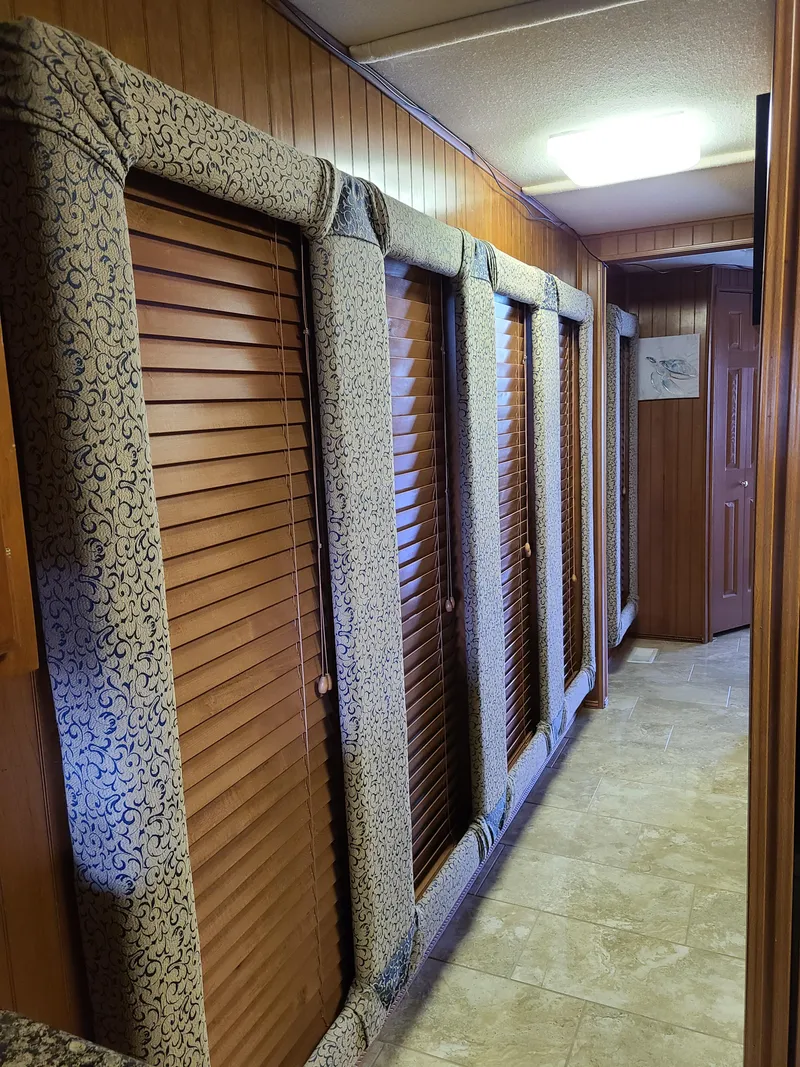 Slide: The Image of Interior hallway of a 2003 Monticello River Yacht with wooden paneling and padded door frames. - 21